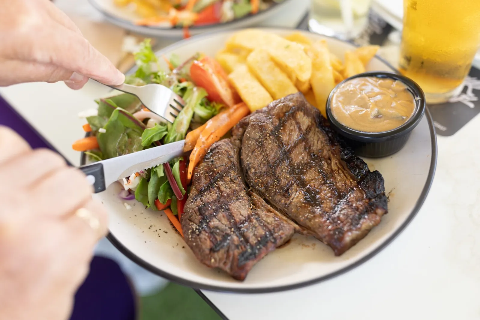 A grilled steak with chips and salad